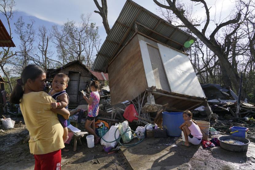 Warga berdiri di tengah rumah yang rusak akibat Topan Rai di Talisay, provinsi Cebu, Filipina tengah pada Sabtu, 18 Desember 2021. Jumlah korban meninggal akibat topan Rai yang melanda Filipina terus bertambah.