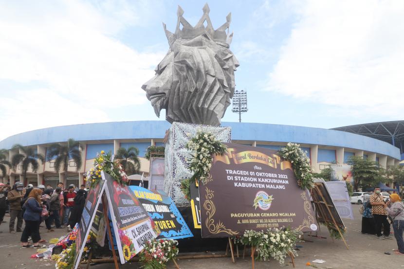 Warga berdoa di patung Singa Tegar kawasan Stadion Kanjuruhan yang dipenuhi karangan bunga di Malang, Jawa Timur, Senin (3/10/2022). Mensos Risma mengatakan tragedi Kanjuruhan menjadi bencana sosial.