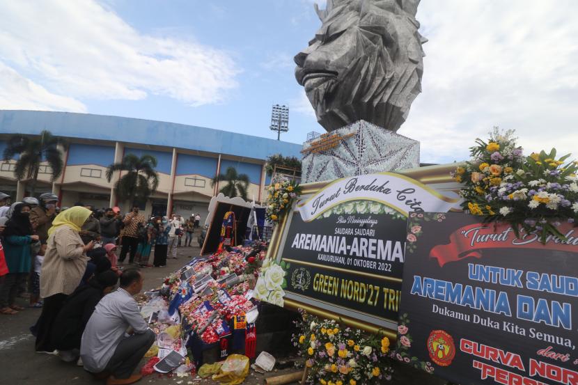 Warga berdoa di patung Singa Tegar kawasan Stadion Kanjuruhan yang dipenuhi karangan bunga di Malang, Jawa Timur, Senin (3/10/2022). Pasca kerusuhan pada pertandingan Arema FC melawan Persebaya sejumlah karangan bunga dari berbagai kalangan terus berdatangan di tempat tersebut sebagai ungkapan duka cita atas banyaknya korban jiwa. 