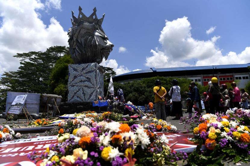 Warga berdoa di sekitar Patung Singa Stadion Kanjuruhan, Malang, Jawa Timur, Selasa (4/10/2022). Hari ketiga pascakerusuhan di stadion itu, puluhan karangan bunga duka dari berbagai kalangan memenuhi halaman stadion begitu pula warga terus berdatangan untuk mendoakan korban yang meninggal dalam kerusuhan itu.