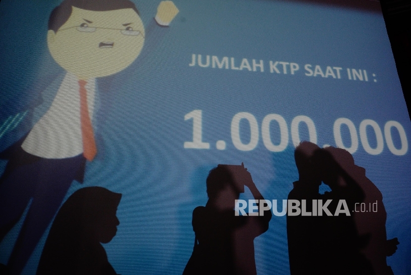 Warga berfoto di depan layar bertuliskan jumlah dukungan KTP sebanyak 1 juta di Sekretariat Teman Ahok, Jakarta, Ahad (19/6). 