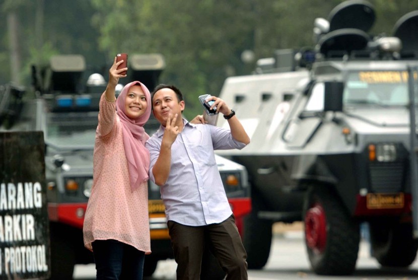 Warga berfoto di depan panser yang diparkirkan di dekat gedung Mahkamah Konstitusi (MK) Jalan Merdeka Barat, Jakarta Pusat, Kamis (21/8). Hari ini MK akan menggelar sidang putusan perselisihan hasil pemilihan umum (PHPU) presiden dan wakil presiden.