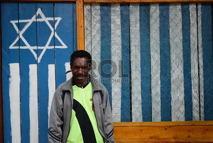  Warga berfoto di depan rumah dengan logo Israel atau Bintang Daud di Tolikara, Papua, Jumat (24/7).  (Republika/Raisan Al Farisi)