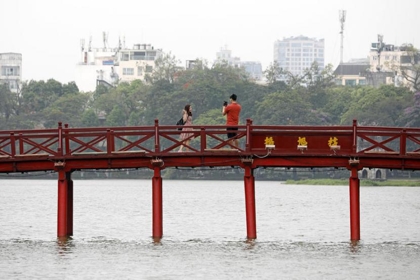 Warga berfoto di Jembatan The Huc, di Hanoi, Vietnam, Jumat (15/5). Kehidupan mulai kembali normal di Vietnam. Sejumlah tempat wisata dibuka kembali pascaperjuangan melawan pandemi corona.