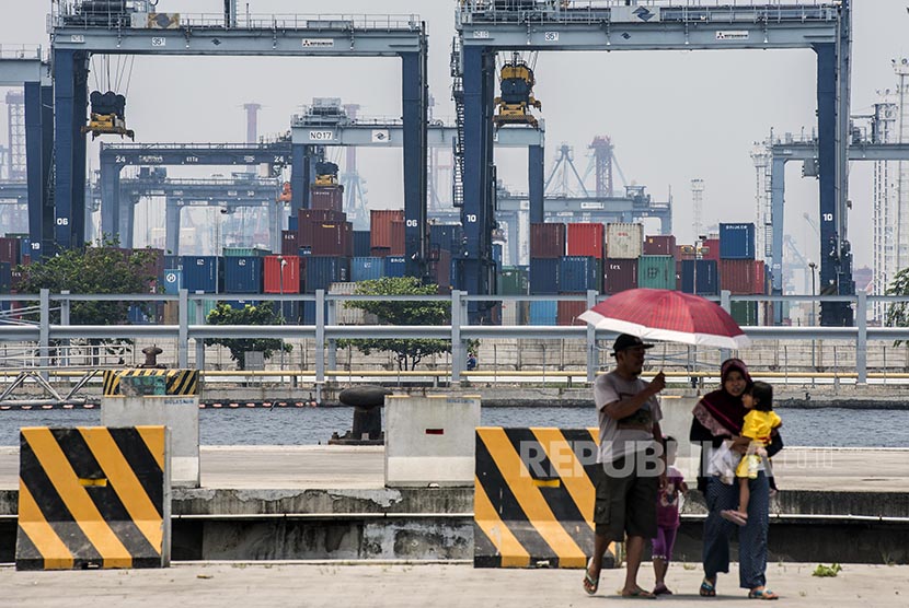 Warga berjalan dengan latar belakang suasana pelabuhan peti kemas di Pelabuhan Tanjung Priok, Jakarta, Selasa (18/10). 