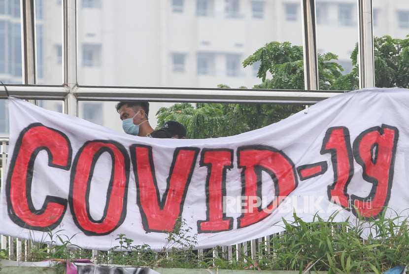 Warga berjalan dengan latar depan spanduk bertuliskan COVID-19 di jalan Margonda, Depok, Jawa Barat, Kamis (12/3/2020).(Antara/Asprilla Dwi Adha)