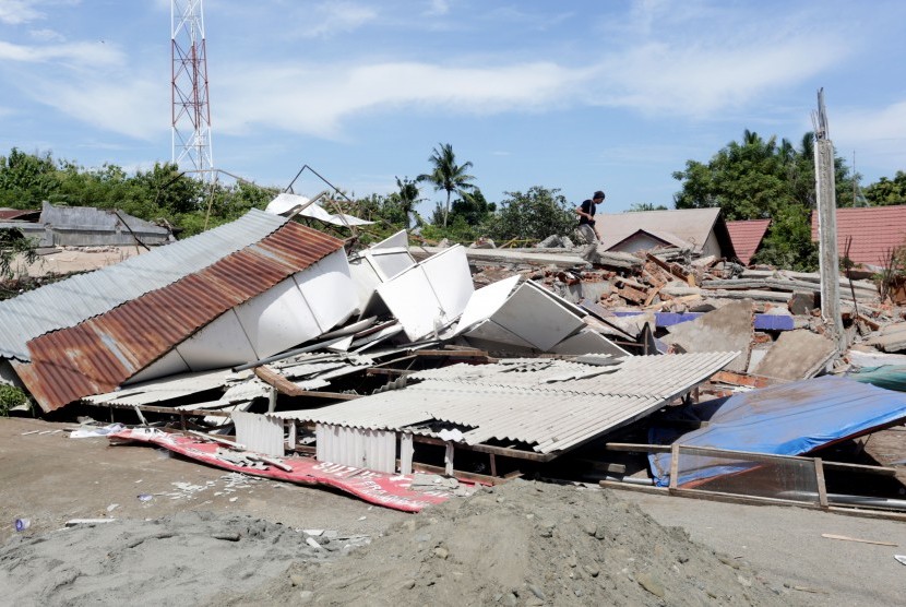 Warga berjalan di atas bangunan ruko yang runtuh akibat gempa 6.5 SR, di Meuredu, Pidie Jaya, Aceh, Rabu (7/12). 