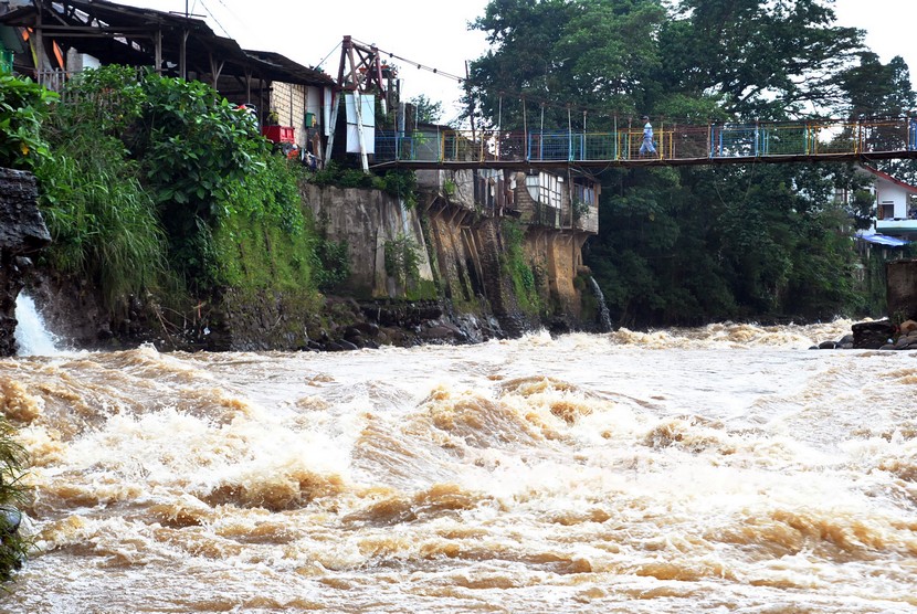Warga berjalan di atas jembatan yang arus airnya deras, di  Kota Bogor. (Ilustrasi)