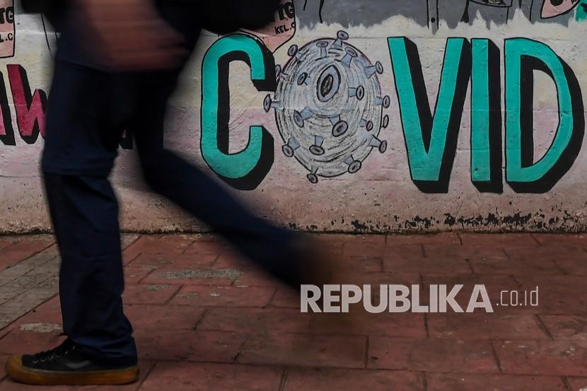 Warga berjalan di dekat mural bertema pencegahan penyebaran Covid-19 di Jakarta. Serologi survei yang dilakukan di Indonesia menunjukkan 86,6 persen penduduk sudah memiliki antibodi terhadap Covid-19. 