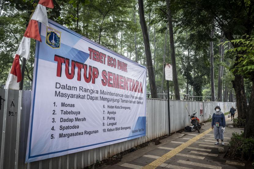 Warga berjalan di dekat spanduk informasi penutupan sementara Tebet Eco Park di Tebet, Jakarta, Rabu (15/6/2022). Pemprov DKI Jakarta melakukan penutupan sementara tempat tersebut hingga akhir Juni 2022 dalam rangka pemeliharaan taman dan perbaikan fasilitas.