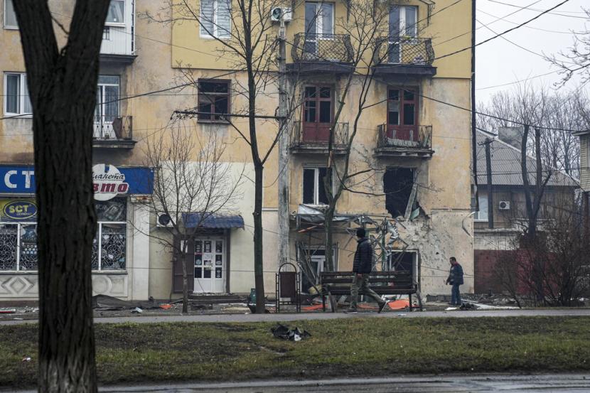 Warga berjalan di depan apartemen yang hancur di Kota Mariupol, Ukraina, Rabu (2/3/2022).