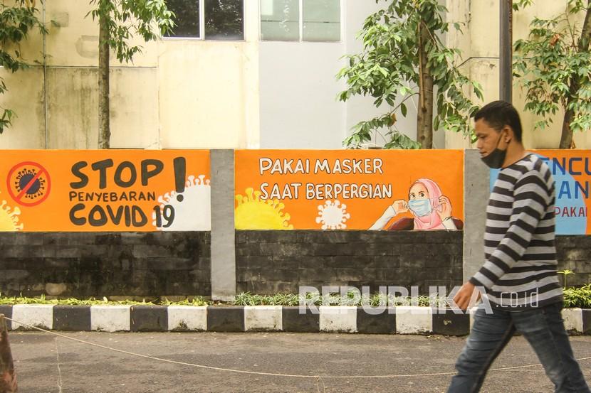 Warga berjalan di depan mural dengan tema COVID-19 di halaman Balai Kota Depok, Depok, Jawa Barat, (ilustrasi).