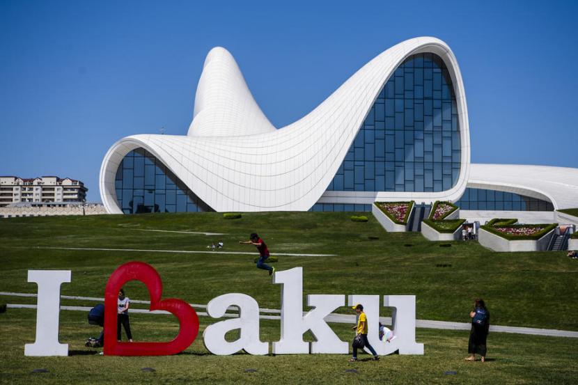 Warga berjalan di depan papan reklame Euro 2020 di dekat Pusat Kebudayaan Heydar Aliyev di Baku, Azerbaijan, pada 9 Juni 2021. Azerbaijan mulai memvaksin penduduknya pada Januari 2021 dengan vaksin Sinovac. 