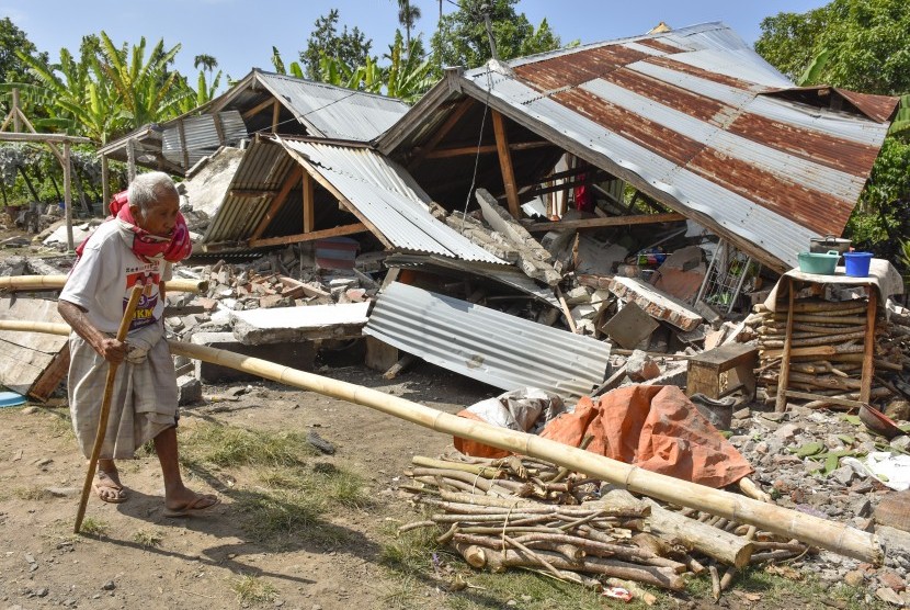 Warga berjalan di depan rumah yang roboh akibat gempa di Desa Sajang, Kecamatan Sembalun, Selong, Lombok Timur, NTB, Ahad (29/7).