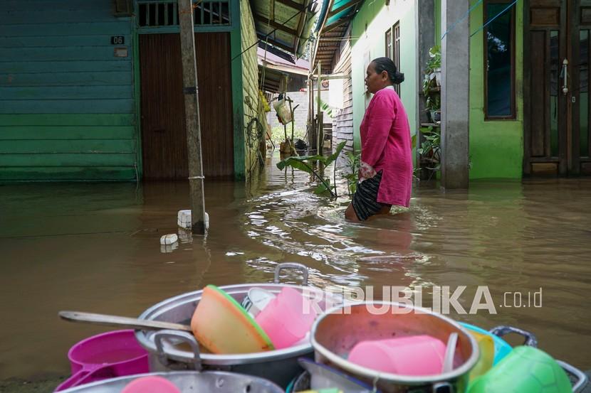 Warga berjalan di depan rumahnya yang terendam banjir di Baning Kota, Kabupaten Sintang, Kalimantan Barat, Senin (15/11/2021). Banjir yang berlangsung hampir empat pekan tersebut berdampak pada terhambatnya roda perekonomian setempat dan aktivitas warga sehari-hari. 