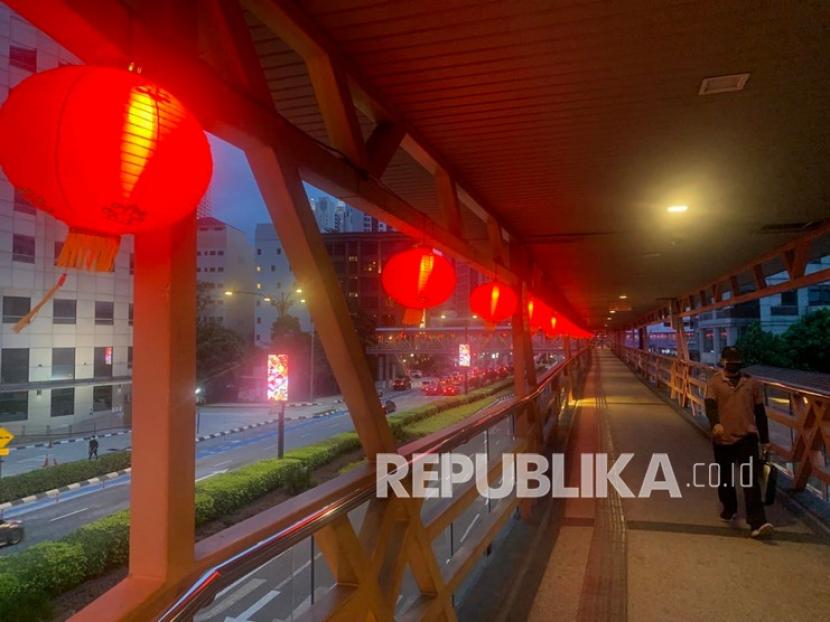 Warga berjalan di jembatan berhias lampu lampion di Jalan Raja Laut Kuala Lumpur, Malaysia, Sabtu (8/1/2022). Dewan pemulihan Covid-19 Malaysia pada Selasa (8/2/2022) telah merekomendasikan pembukaan kembali perbatasan negara secara penuh mulai 1 Maret.