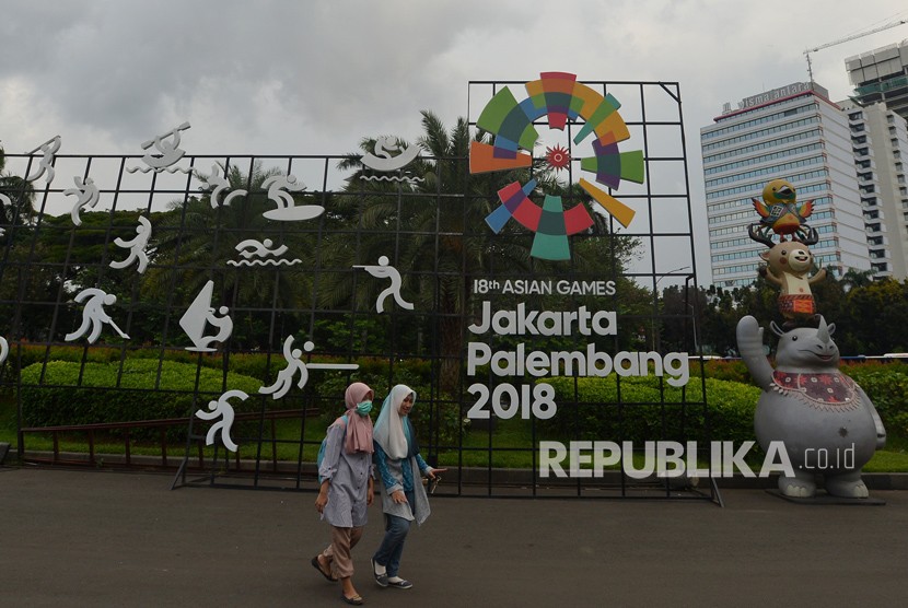 Warga berjalan di samping display promosi Asian Games 2018 di Kawasan Jalan Merdeka Selatan, Jakarta, Jumat (20/4).