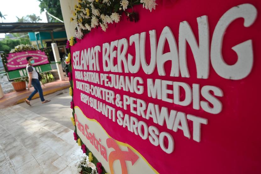Warga berjalan di samping karangan bunga dukungan untuk tenaga medis dan staf Rumah Sakit Penyakit Infeksi (RSPI) Sulianti Saroso di Jakarta.