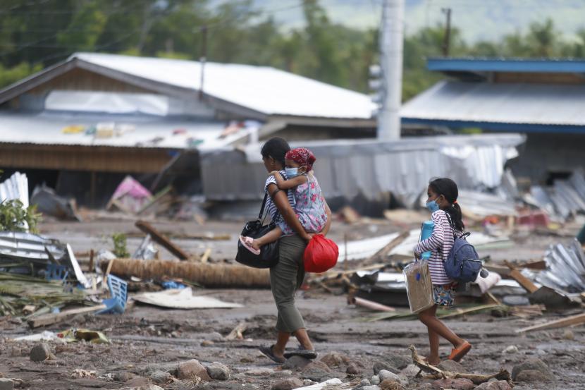 Warga berjalan di samping sisa-sisa rumah yang rusak di Kota Datu Odin Sinsuat, Maguindanao, Filipina selatan pada Ahad, 30 Oktober 2022. 