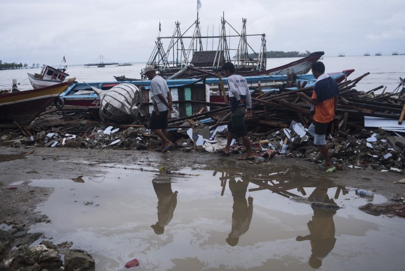 Warga berjalan di sisa-sisa bangunan dan kapal yang rusak diterjang tsunami Selat Sunda di Sumur, Pandeglang, Banten, Kamis (3/1/2019).