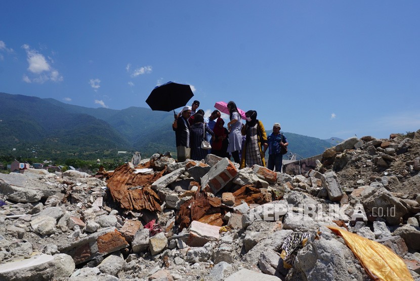 Warga berjalan disekitar lokasi bekas pemukiman mereka yang hancur akibat bencana gempa dan likuefaksi di Perumnas Balaroa, Palu, Sulawesi Tengah, Ahad (11/8/2019). Lagu 