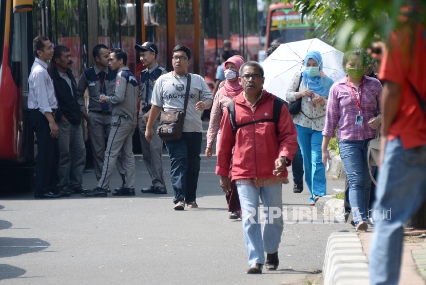 Warga berjalan kaki saat Ribuan sopir taksi dan angkutan umum lain melakukan aksi di Jakarta, Selasa (22/3). (Republika/Yasin Habibi)