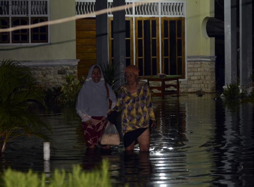 Warga berjalan keluar dari rumahnya yang tergenang banjir (ilustrasi). BPBD Lampung Selatan mencatat rumah warga yang dilanda banjir.