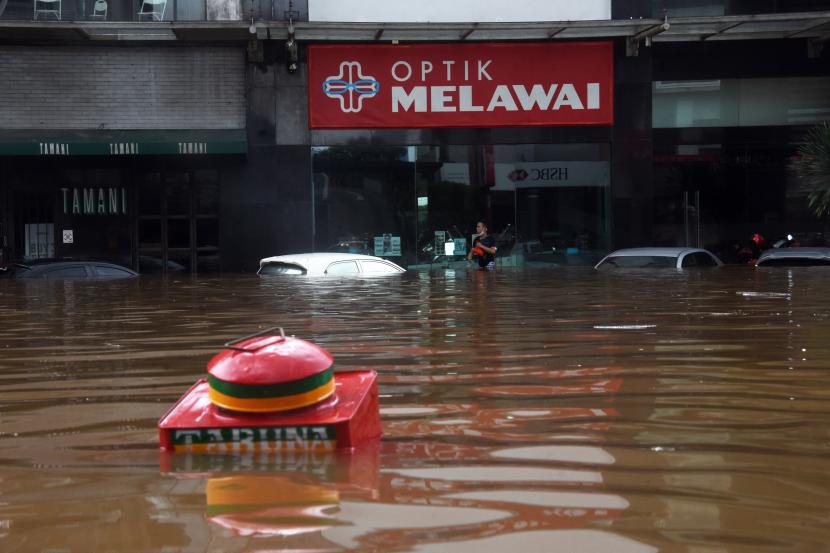 Warga berjalan melewati banjir di kawasan Kemang, Jakarta Selatan, Sabtu (20/2/2021). Banjir yang terjadi akibat curah hujan tinggi serta drainase yang buruk membuat kawasan Kemang banjir setinggi 1,5 meter.