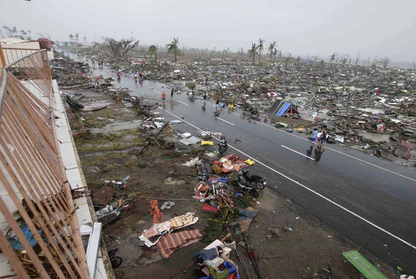  Warga berjalan melewati pemukiman yang hancur akibat Topan Haiyan di kota Tacloban, Leyte provinsi Leyte, Filipina tengah, Ahad (10/11).  (AP/Bullit Marquez)