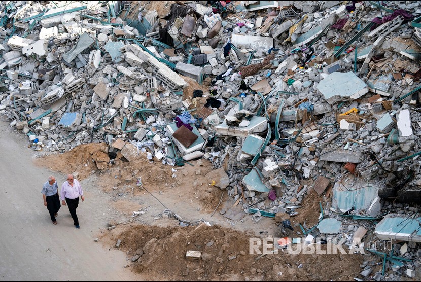 Ini Dampak Pendudukan Israel Terhadap Perekonomian Palestina. Warga berjalan melewati reruntuhan gedung Al Jalaa yang hancur oleh serangan udara Israel, Gaza, Jumat (21/5) waktu setempat.  Sejumlah media internasional menempati gedung Al-Jalaa termasuk kantor berita Associated Press yang telah berkantor disana selama 15 tahun.