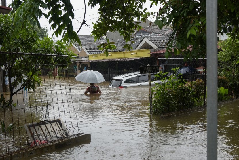 Warga berjalan melintasi banjir di perumahan Taman Narogong Indah, Bekasi, Jawa Barat, Rabu (1/1/2020). Hujan lebat sepanjang malam tahun baru yang mengguyur Bekasi dan kawasan sekitarnya mengakibatkan banjir terjadi di sejumlah titik. 