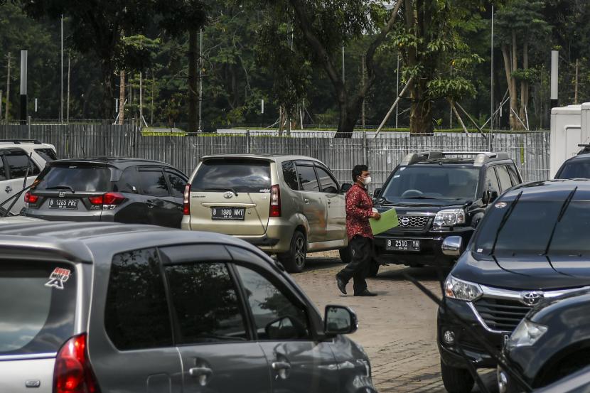 Dishub DKI: Tarif Parkir Maksimal Kendaraan Masih Usulan. Warga berjalan melintasi deretan mobil yang terparkir di pelataran parkir IRTI Monas, Jakarta.
