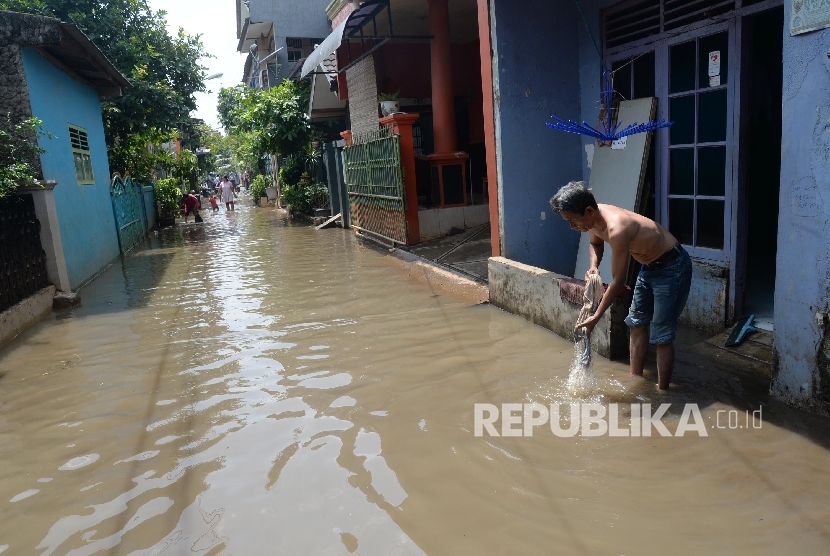 Warga berjalan melintasi genangan air saat banjir di permukiman warga di kawasan Cipinang Melayu, Jakarta Timur.