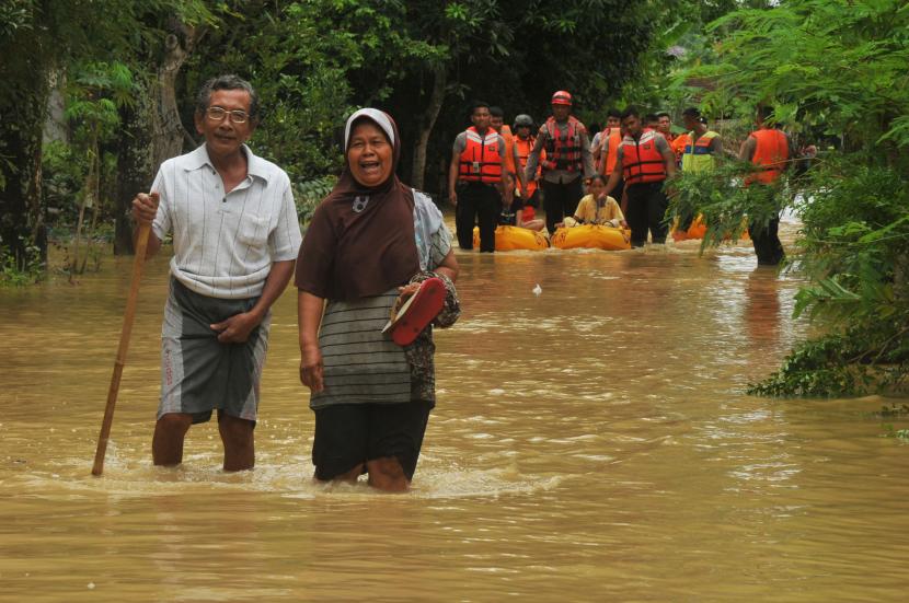 Warga berjalan melintasi jalan banjir yang menggenangi Desa Tamansari di Jaken, Pati, Jawa Tengah, Sabtu (15/10/2022).(Ilustrasi)