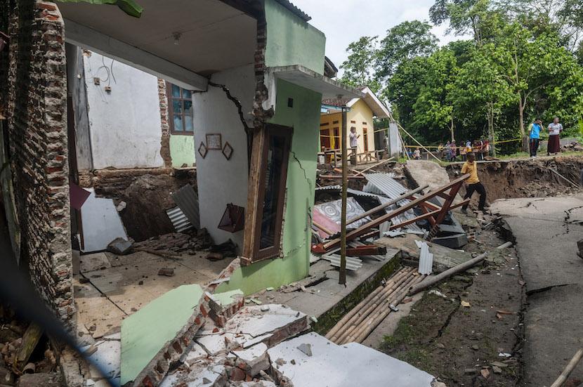 Warga berjalan melintasi rumah yang rusak akibat pergerakan tanah di Desa Cilangkap, Kabupaten Lebak, Provinsi Banten, Sabtu (11/6/2022). 