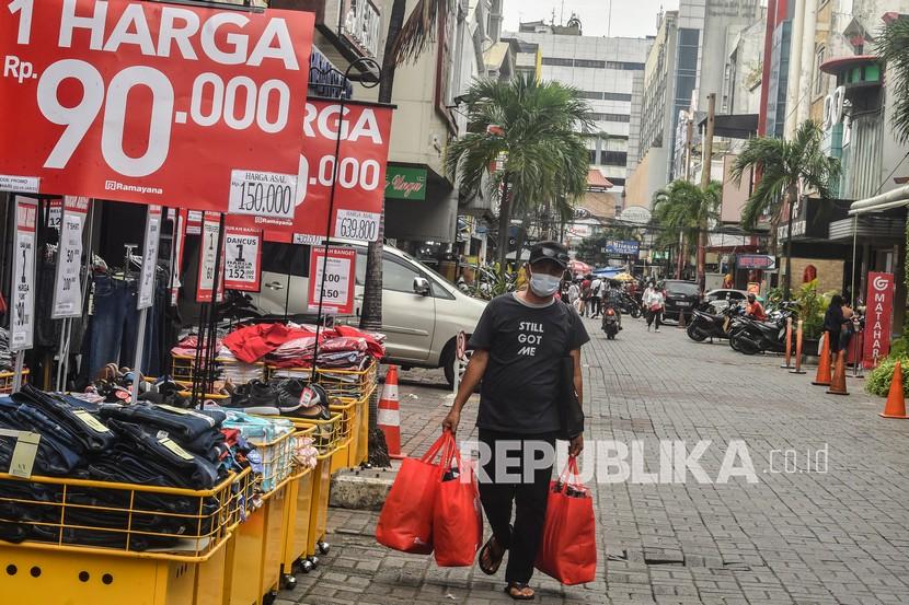 Warga berjalan membawa belanjaannya di kawasan Pasar Baru, Jakarta Pusat, Jumat (22/1/2021).