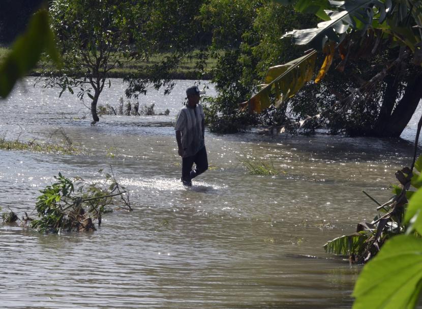 Warga menerobos banjir (ilustrasi). BMKG Provinsi Lampung meminta warga setempat mewaspadai bencana hidrometeorologi seperti banjir dan tanah longsor di tengah puncak musim hujan.