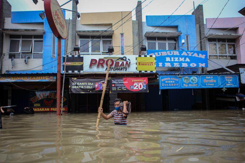 Warga berjalan menerobos banjir di kawasan Regency, Pasar Kemis, Kabupaten Tangerang, Banten, Sabtu (20/2/2021). Hujan deras yang mengguyur sejak Sabtu (20/2) dini hari menyebabkan kawasan tersebut terendam banjir hingga 1,5 meter.