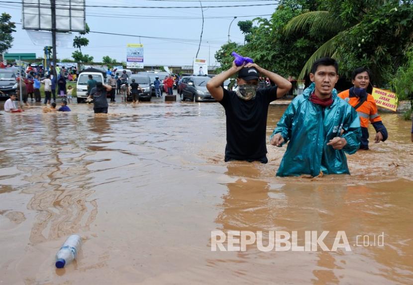 Warga berjalan menerobos banjir di Kotasari, Grogol, Cilegon, Banten, Senin (4/5/2020). Banjir yang terjadi akibat tanggul Kali Ciore jebol setelah diguyur hujan sejak Minggu (3/5) malam itu mengakibatkan ratusan rumah dan jalan terendam air setinggi 40-110 centimeter. 
