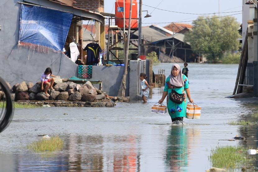 Warga berjalan menerobos banjir rob yang merendam pemukiman di Desa Eretan Wetan, Indramayu, Jawa Barat.