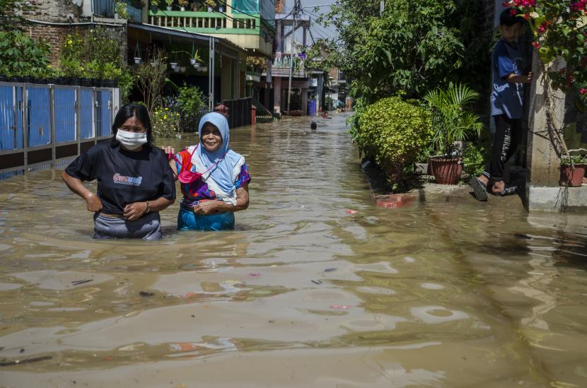 Warga berjalan pada genangan banjir di Dayeuhkolot, Kabupaten Bandung, Jawa Barat.