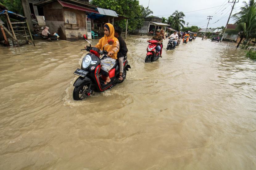Warga berkendara sepeda motor menerobos banjir di Desa Meunasah Joek, Lhoksukon, Aceh Utara, Aceh, Senin (28/2/2022). Menurut data dari Badan Penanggulangan Bencana Daerah (BPBD) Aceh Utara, banjir akibat luapan sungai yang tidak mampu menampung kenaikan air karena tingginya intensitas hujan sejak dua hari terakhir itu merendam lima kecamatan dan sebanyak 1.340 kepala keluarga mengungsi.