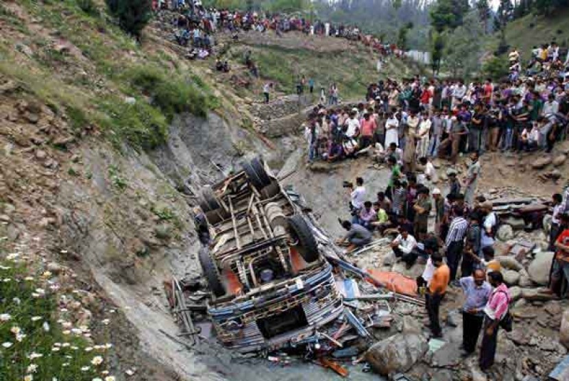  Warga berkerumun menyaksikan bus sekolah yang jatuh di Distrik Baramulla, Kashmir, India, Rabu (11/7).