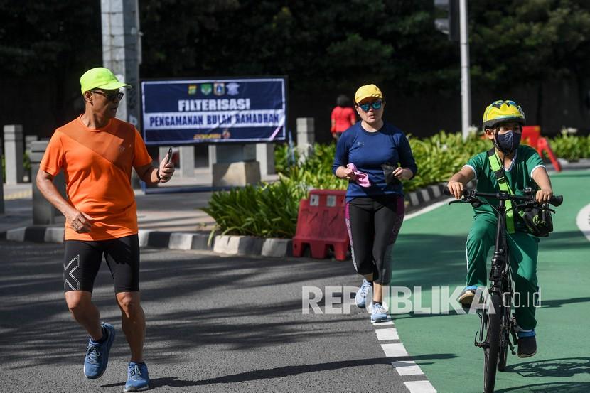 Warga berlari dan bersepeda di kawasan Bundaran HI, Jakarta, Ahad (3/4/2022). Aktivitas olahraga warga ibu kota pada hari pertama puasa Ramadan terpantau lebih sepi dibanding hari Minggu sebelum-sebelumnya.