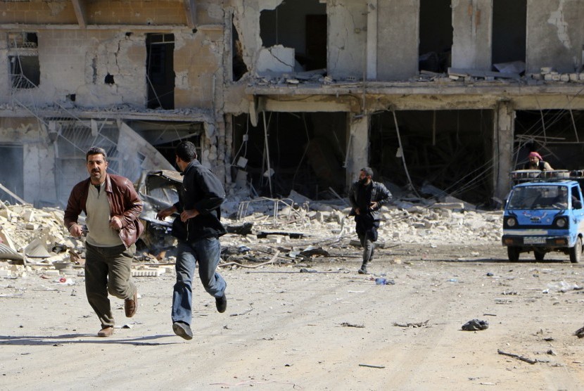 Warga berlarian saat bom dalam tong menghantam sebuah bangunan di Aleppo. Bom ini ditengarai dijatuhkan oleh pesawat angkatan udara Suriah.