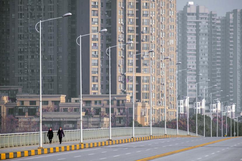 Warga bermasker berjalan di pusat Kota Wuhan, Provinsi Hubei, China. Hubei akan terapkan sistem 'kode kesehatan' atau pemantauan berbasis ponsel.(AP Photo/Arek Rataj)