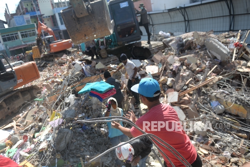 Warga bersama aparat melakukan evakuasi lanjutan di reruntuhan ruko di Pasar Meureudu, Pidie Jaya, NAD, Kamis (8/12).
