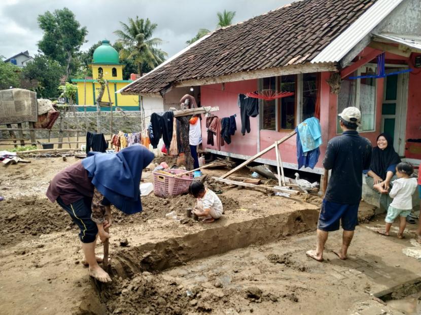 Warga bersama sejumlah relawan membersihkan sisa material lumpur pascabanjir di Desa Mandalakasih, Kecamatan Pameungpeuk, Kabupaten Garut, Selasa (13/10). 