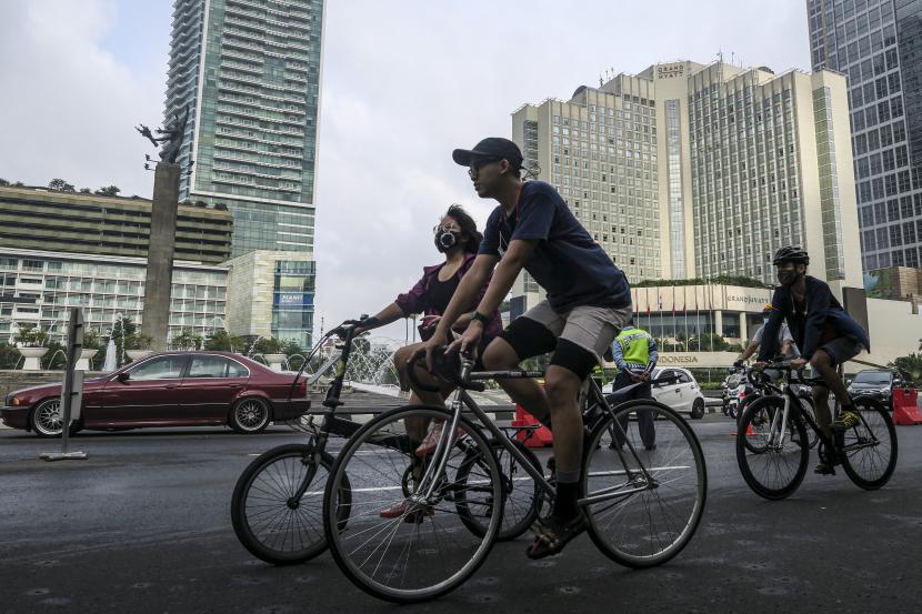 Warga bersepeda melintasi kawasan Bundaran Hotel Indonesia di Jakarta, Ahad (14/2/2021). Meski Pemprov DKI Jakarta menerapkan Pemberlakuan Pembatasan Kegiatan Masyarakat (PPKM) berbasis mikro, namun warga masih ramai berolahraga di jalan protokol ibukota. 