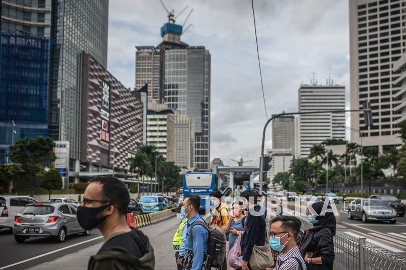Warga bersiap menyeberang Jalan Jenderal Sudirman di Jakarta. Mulai 11 Januari hingga 25 Januari 2021, pemerintah memberlakukan pembatasan kegiatan secara terbatas di Pulau Jawa dan Bali untuk menekan penyebaran kasus positif Covid-19.